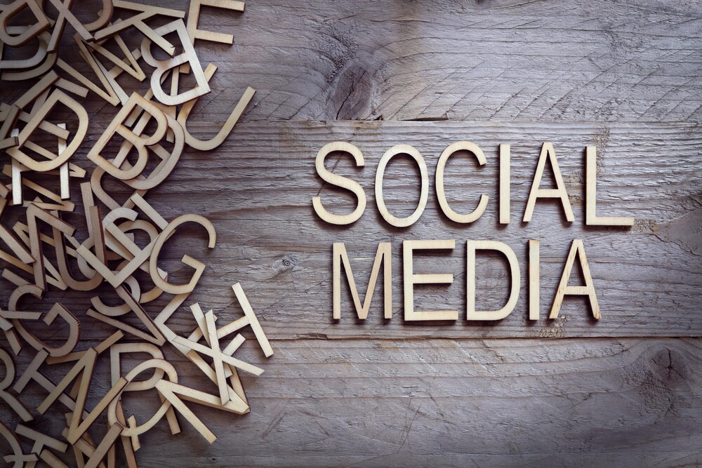 Auf Holzbrettern liegen Buchstaben aus Holz. Diese ergeben die Wörter Social Media.
