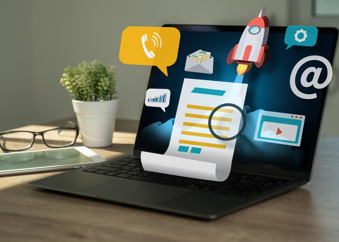 Professionelle Website in Zeiten von Social-Media Laptop auf einem Tisch. Darüber schweben verschiedene Icons