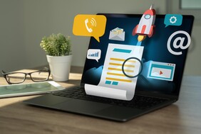 Laptop auf einem Tisch. Darüber schweben verschiedene Icons
