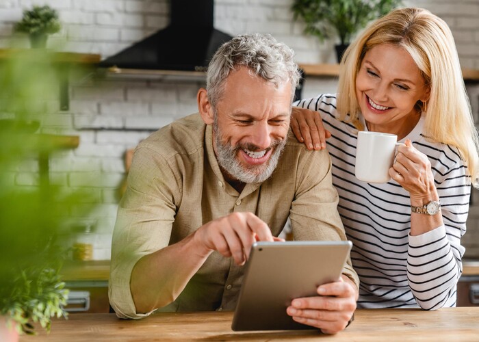 Website für Gemeinde - Barrierefrei und zukunftssicher Ein Mann und eine Frau stehen in einer Küche und sehen lächelnd auf eine Tablet-Computer